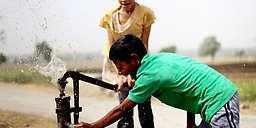 Lekande barn som dricker ur en vattenfontän